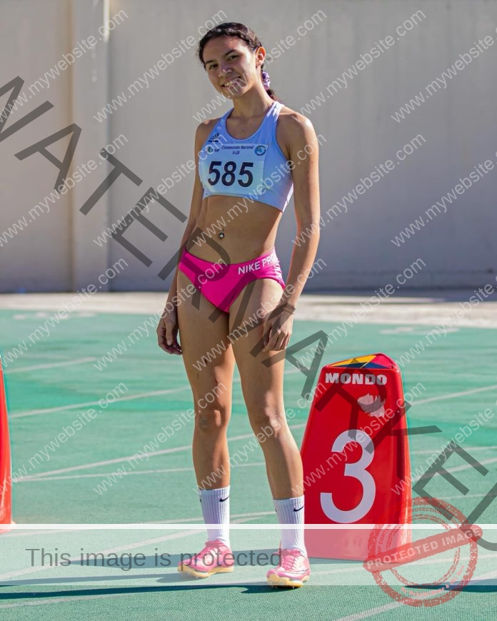 Mariana Casanova standing on track wearing competition bib number 585 with pink shorts.