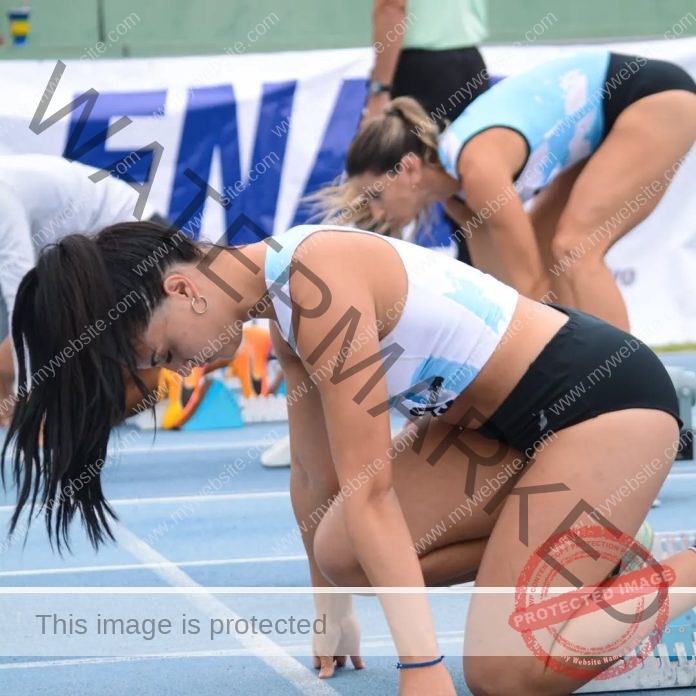 Argentine sprinter Morena Zárate focusing before a race on a vibrant blue track.