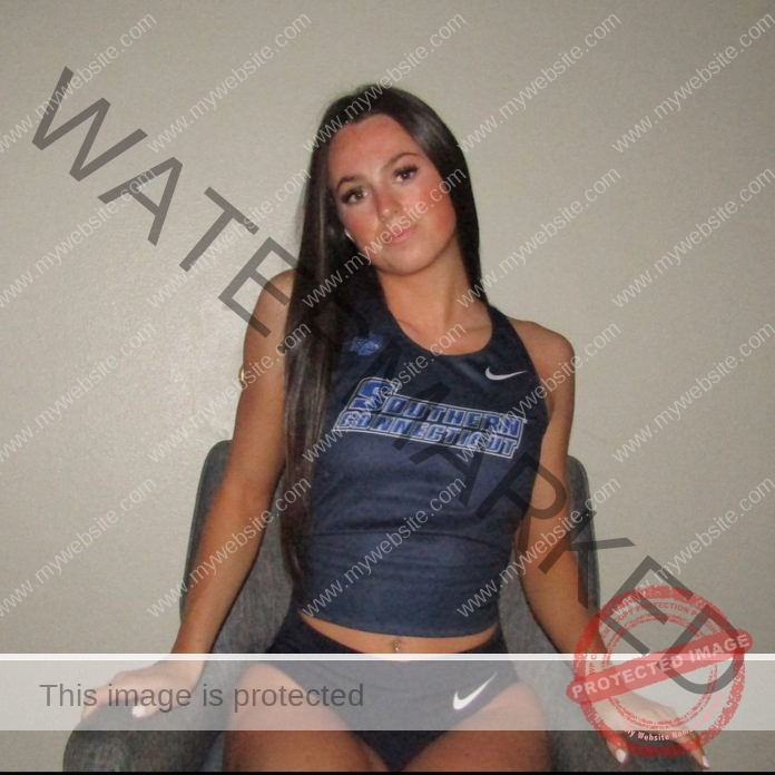 Avery Winters posing in a navy blue athletic crop top and shorts.