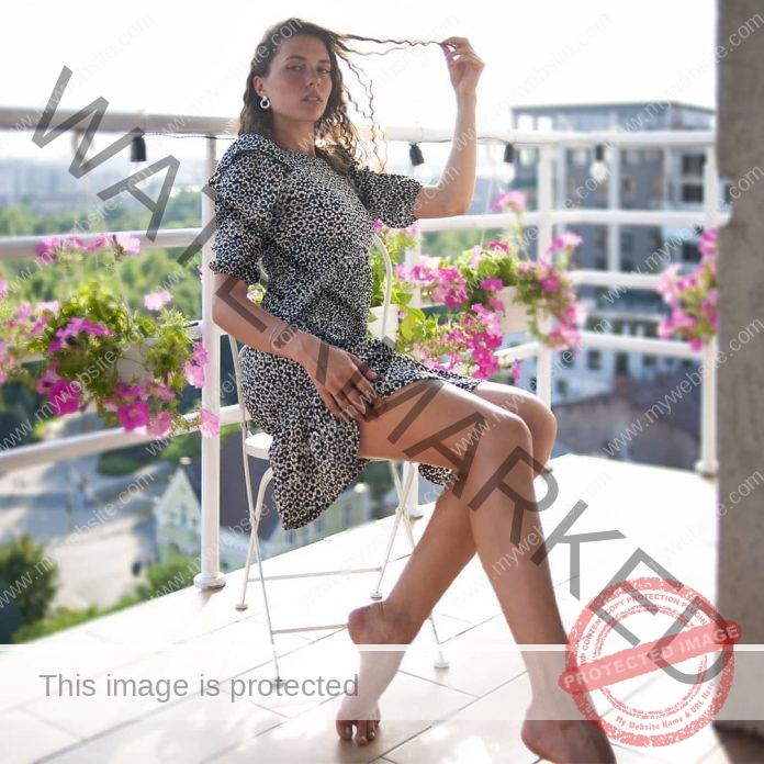 Hanna Onufrieva sitting on balcony with floral garden and cityscape view.