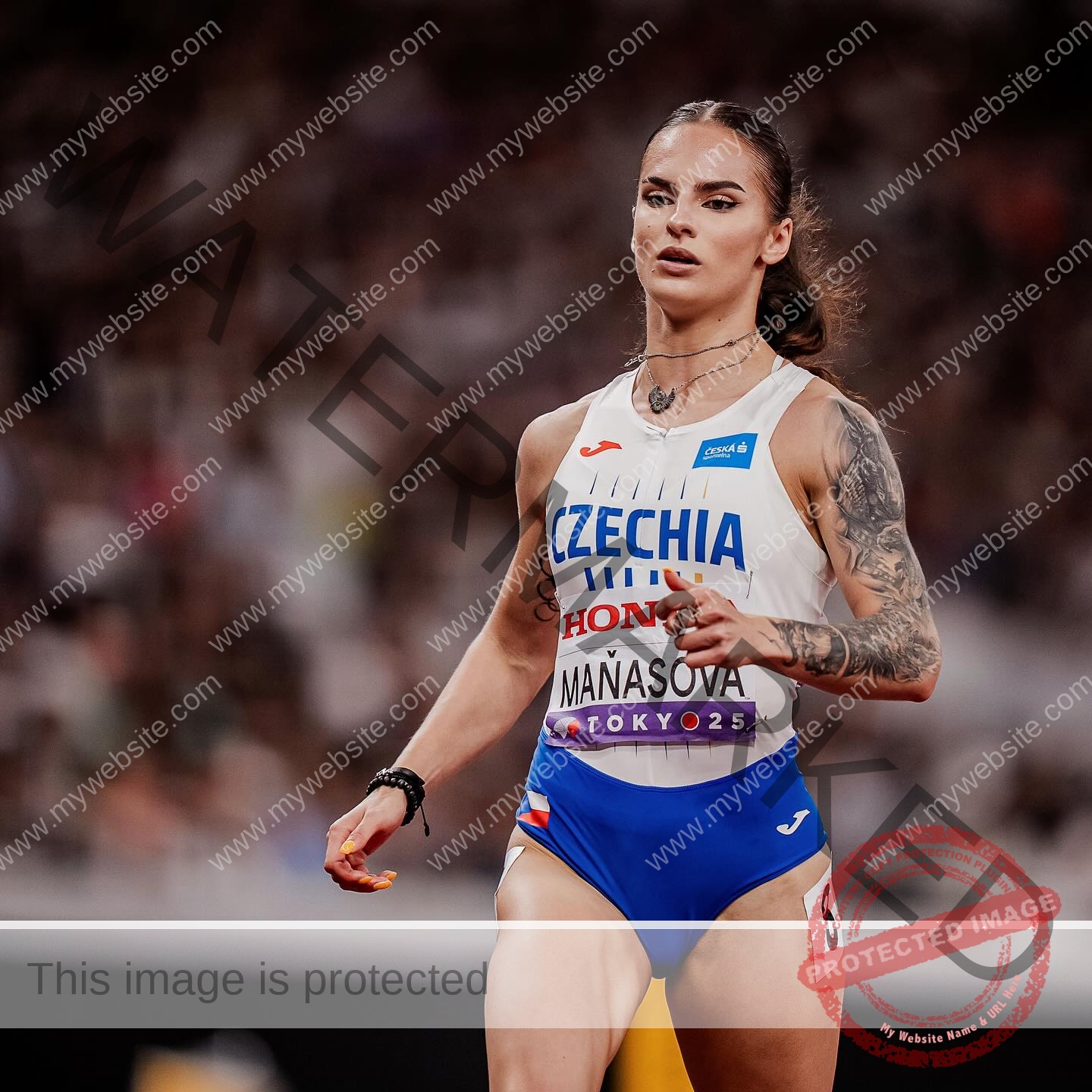 karolina-manasova-czechia-karolina_manasova-391 Karolína Maňasová, a track athlete in a Czechia uniform with tattoos on her left arm, walks on the track looking focused.
