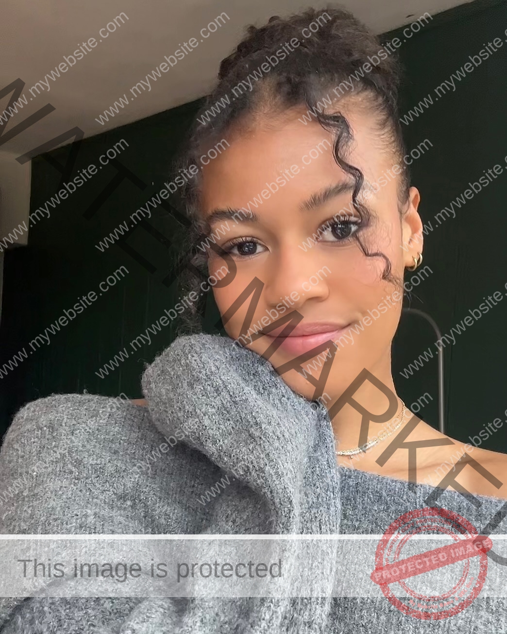 abigail-noruwa-netherlands-abigail_noruwa-u20-x-00054 Abigail Noruwa, track star from the Netherlands, smiles softly with curly hair, gray off-shoulder sweater, and small earrings.