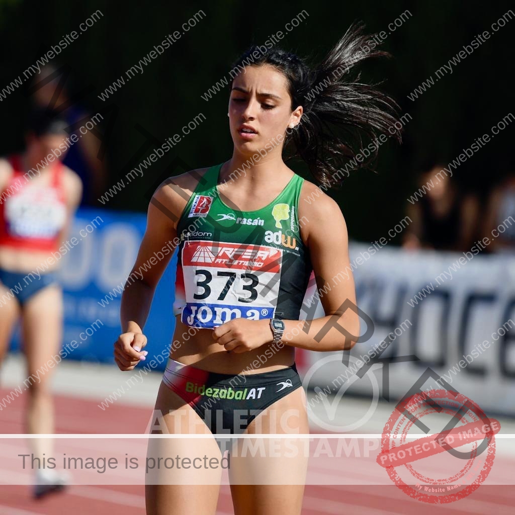 ainhoa-idoiaga-spain-ainhoidoiaga-00292 Ainhoa Idoiaga, track athlete from Spain, wears a green and black uniform with number 373, running on an outdoor track.