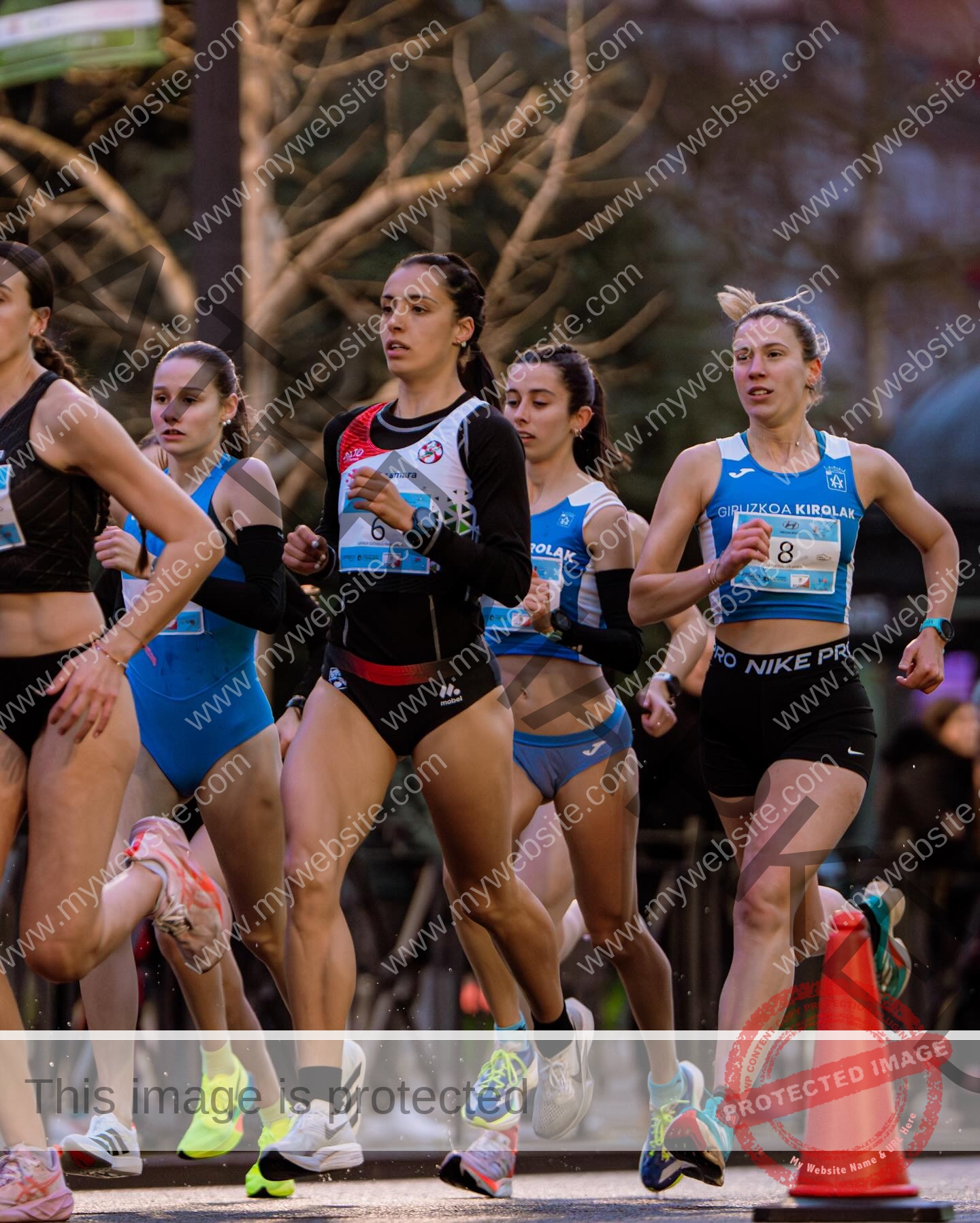 ainhoa-idoiaga-spain-ainhoidoiaga-00438 Ainhoa Idoiaga, track athlete from Spain, a group of female athletes in running gear compete in a road race mid-stride outdoors.