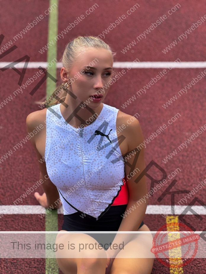 Alina Kyshkina, track athlete from Ukraine, sits on a red running track in Puma gear, blonde hair tied back, gold hoop earrings.
