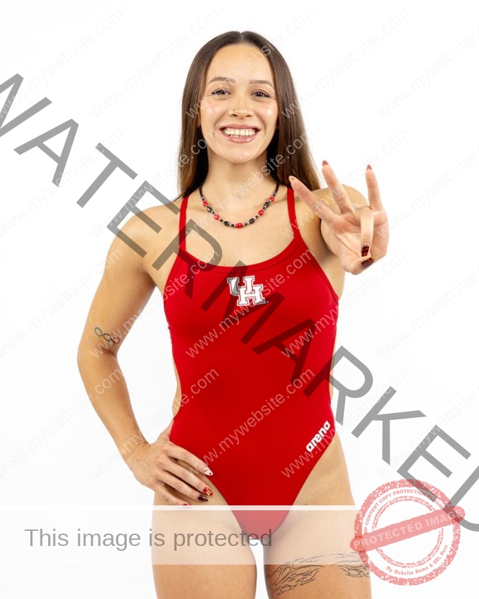 Alondra Ortiz A smiling swimmer, Alondra Ortiz, in a red University of Houston swimsuit flashes a hand sign. Plain white background.