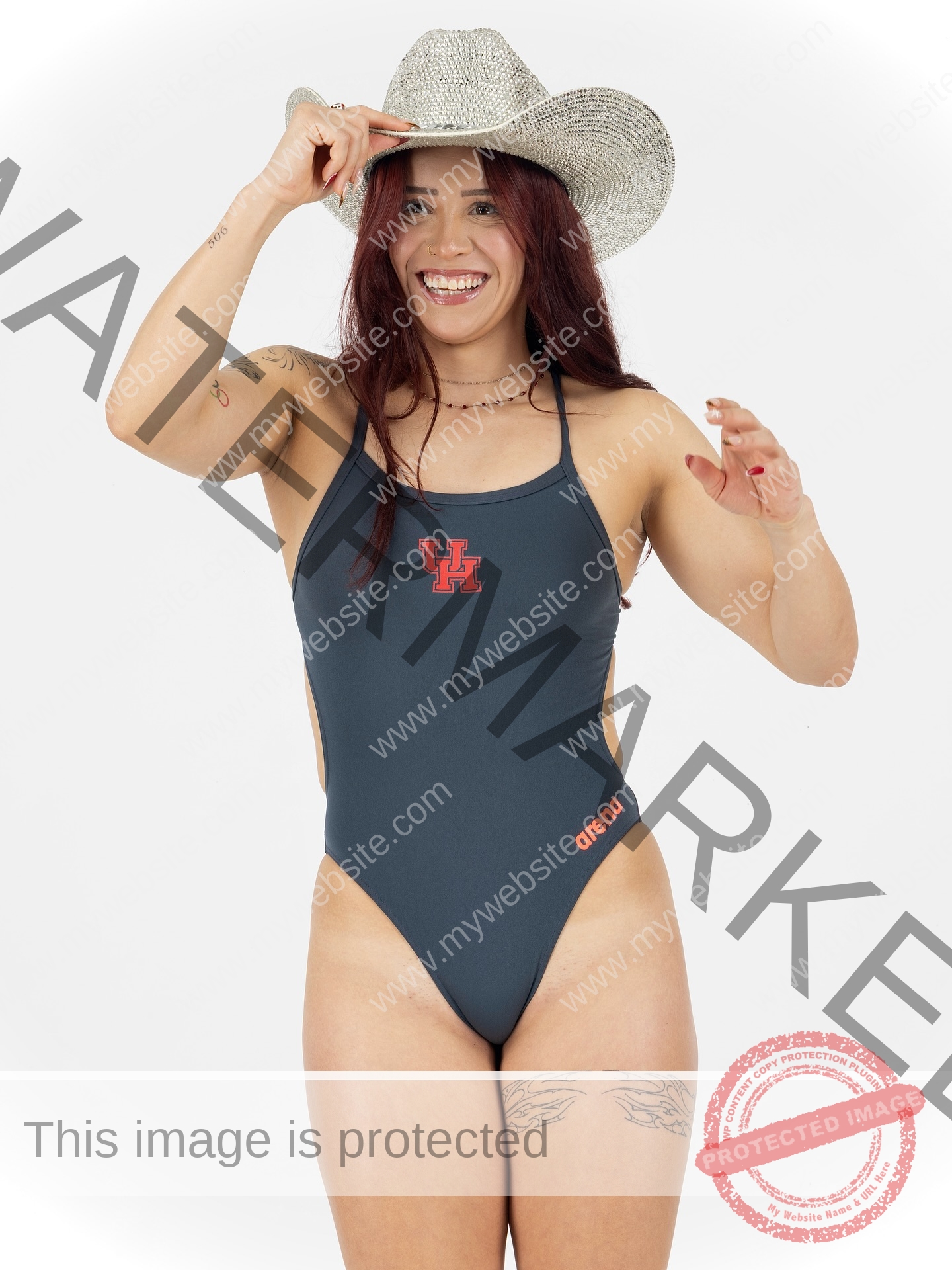 alondra-ortiz-costa-rica-alortizroman-727 Alondra Ortiz, a smiling swimmer in a UH gray one-piece, cowboy hat, and with thigh tattoos, shows Costa Rican pride on white.