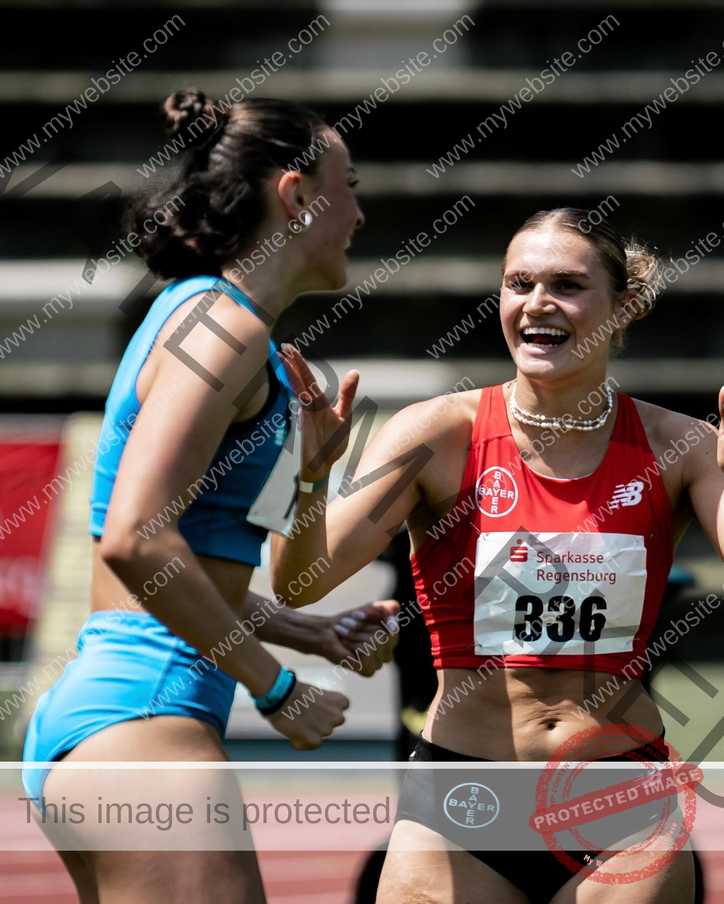 amira-never-germany-amira.never-02783 Amira Never, track star from Germany, smiles and celebrates with another female athlete on a track after a joyful race moment.