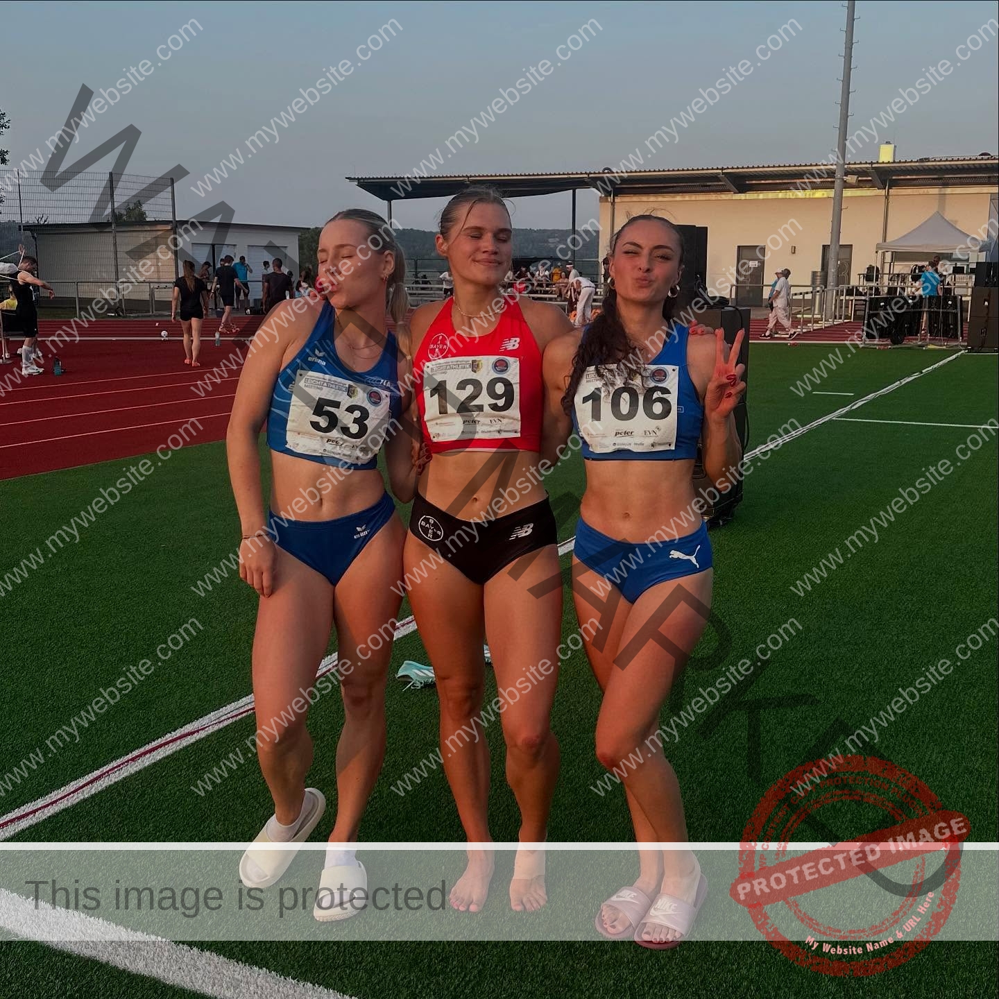 amira-never-germany-amira.never-02797 Amira Never, track star from Germany with two teammates in numbered bibs, posing playfully on a sunlit track.