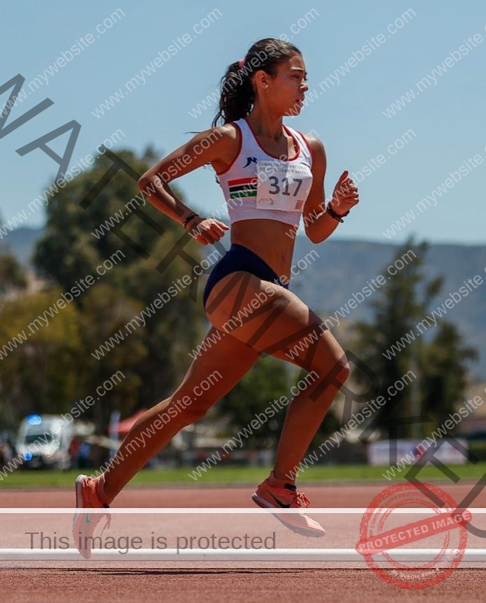 Ampara Herrera Track and field athlete Ampara Herrera, bib 317, runs mid-stride on a Chilean track; blurred trees, mountains behind.