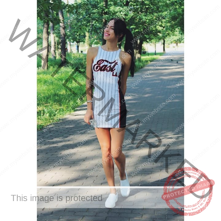 anastasia-bryzgina-ukraine-bryzgina_a-03832 Anastasia Bryzgina, track star from Ukraine, stands on a sun-dappled tree-lined path in a striped dress and white sneakers, smiling.