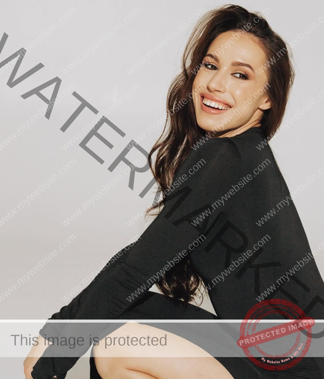anastasia-bryzgina-ukraine-bryzgina_a-04098 Anastasia Bryzgina, track star from Ukraine, with long brown hair in a black dress, sits smiling at the camera against a light background.