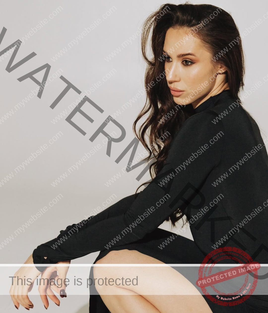 anastasia-bryzgina-ukraine-bryzgina_a-04099 Anastasia Bryzgina, track star from Ukraine, sits sideways on the floor in a black dress, gazing aside with a neutral expression.