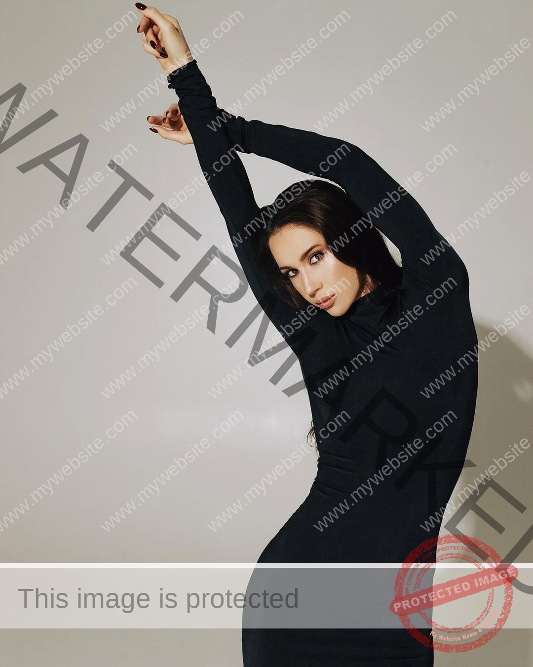 anastasia-bryzgina-ukraine-bryzgina_a-04107 Anastasia Bryzgina, track star from Ukraine, in a fitted black dress poses with arms raised, gazing intensely at the camera.