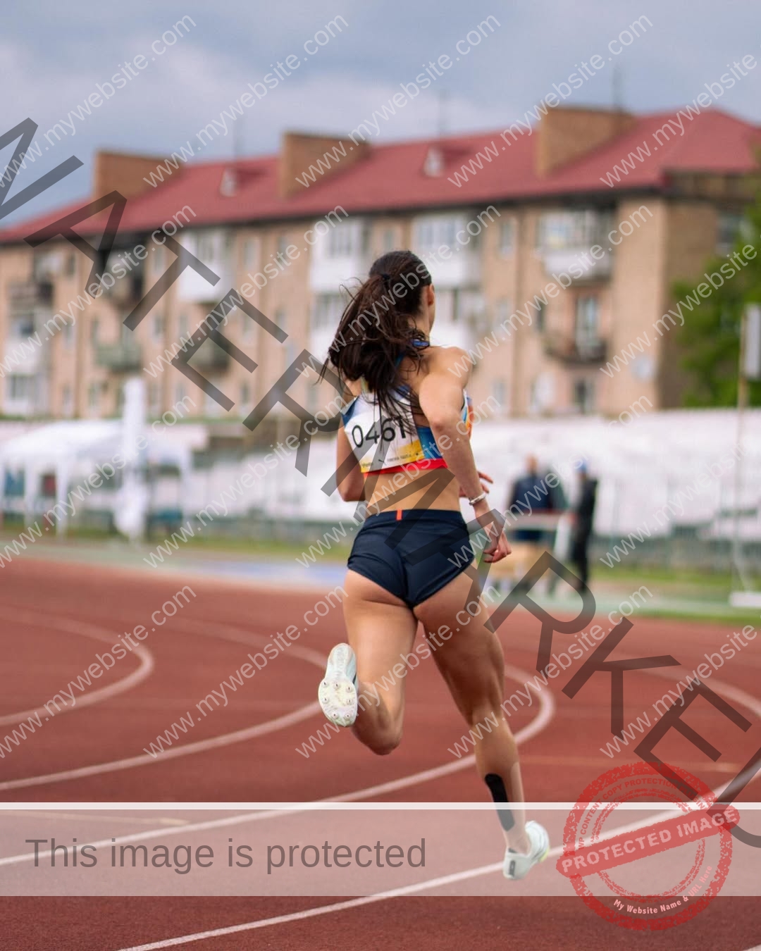 anastasia-bryzgina-ukraine-bryzgina_a-04115 Anastasia Bryzgina, track star from Ukraine, sprints on a red track under cloudy skies, buildings in the background, seen from behind.