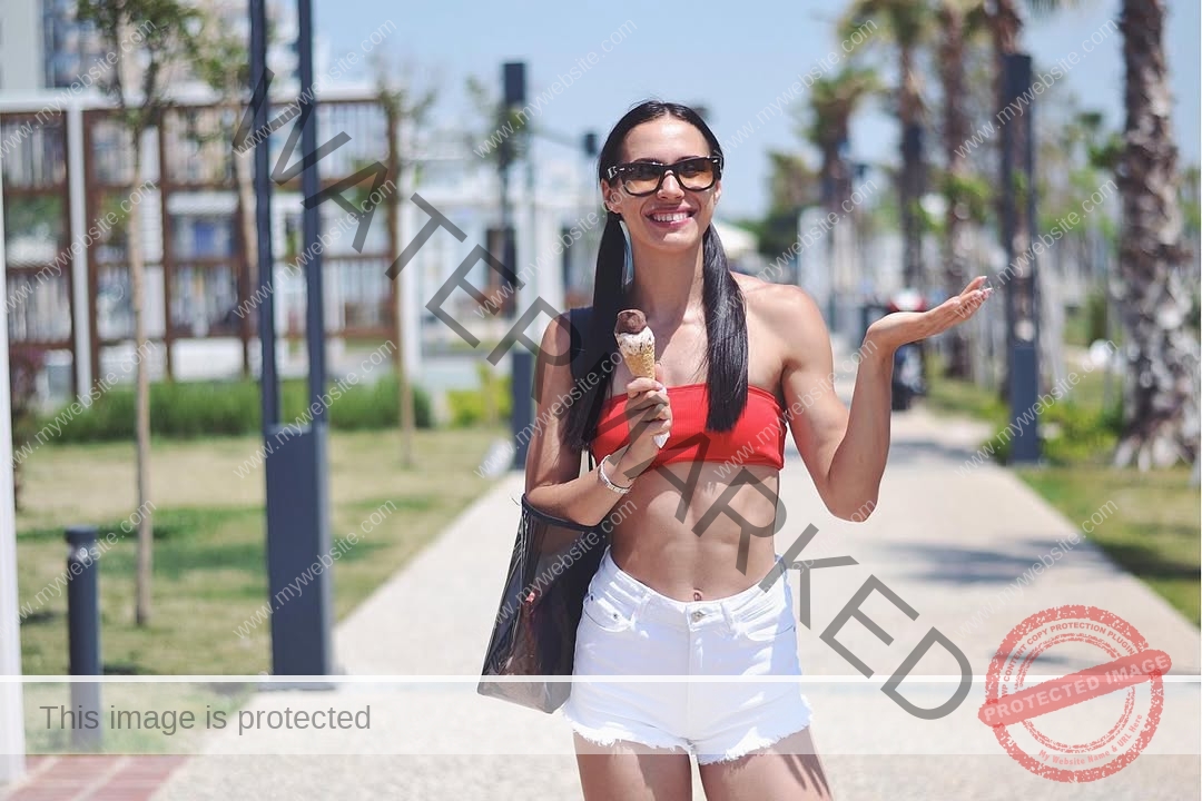 anastasia-bryzgina-ukraine-bryzgina_a-04138 Anastasia Bryzgina, track star from Ukraine, wears sunglasses, a red bandeau top, and white shorts, smiling with ice cream outside.