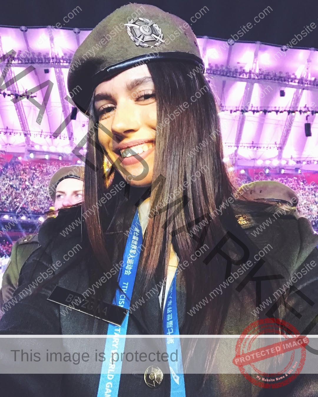 anastasia-bryzgina-ukraine-bryzgina_a-04172 Anastasia Bryzgina, track star from Ukraine, in uniform and beret smiles for a selfie at a stadium event with bright lights.