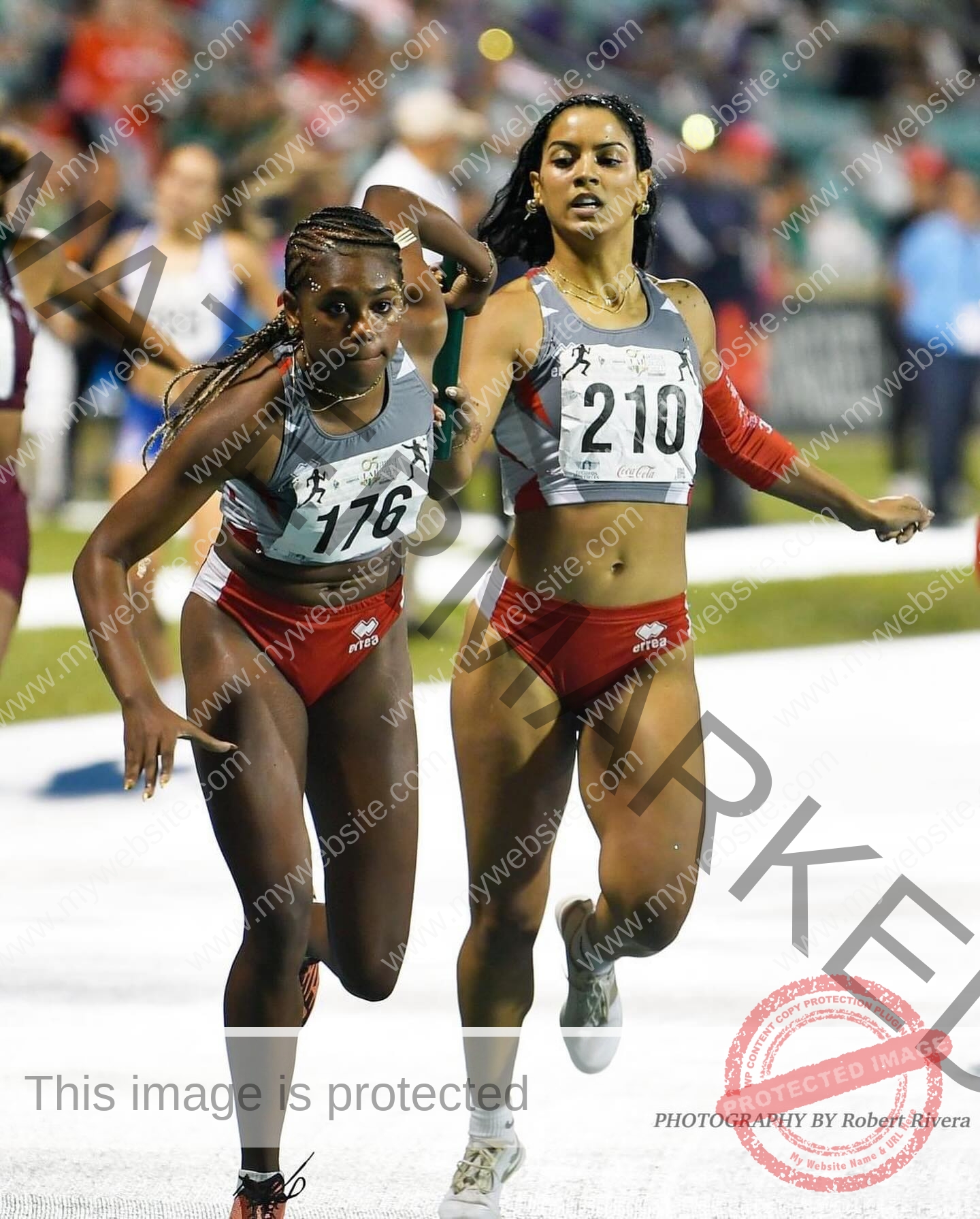 andrea-rivera-aviles-puerto-rico-aandrea.sofiaa-05908 Andrea Rivera Aviles, track athlete from Puerto Rico, passes a relay baton in red shorts and gray top on the track, looking focused.