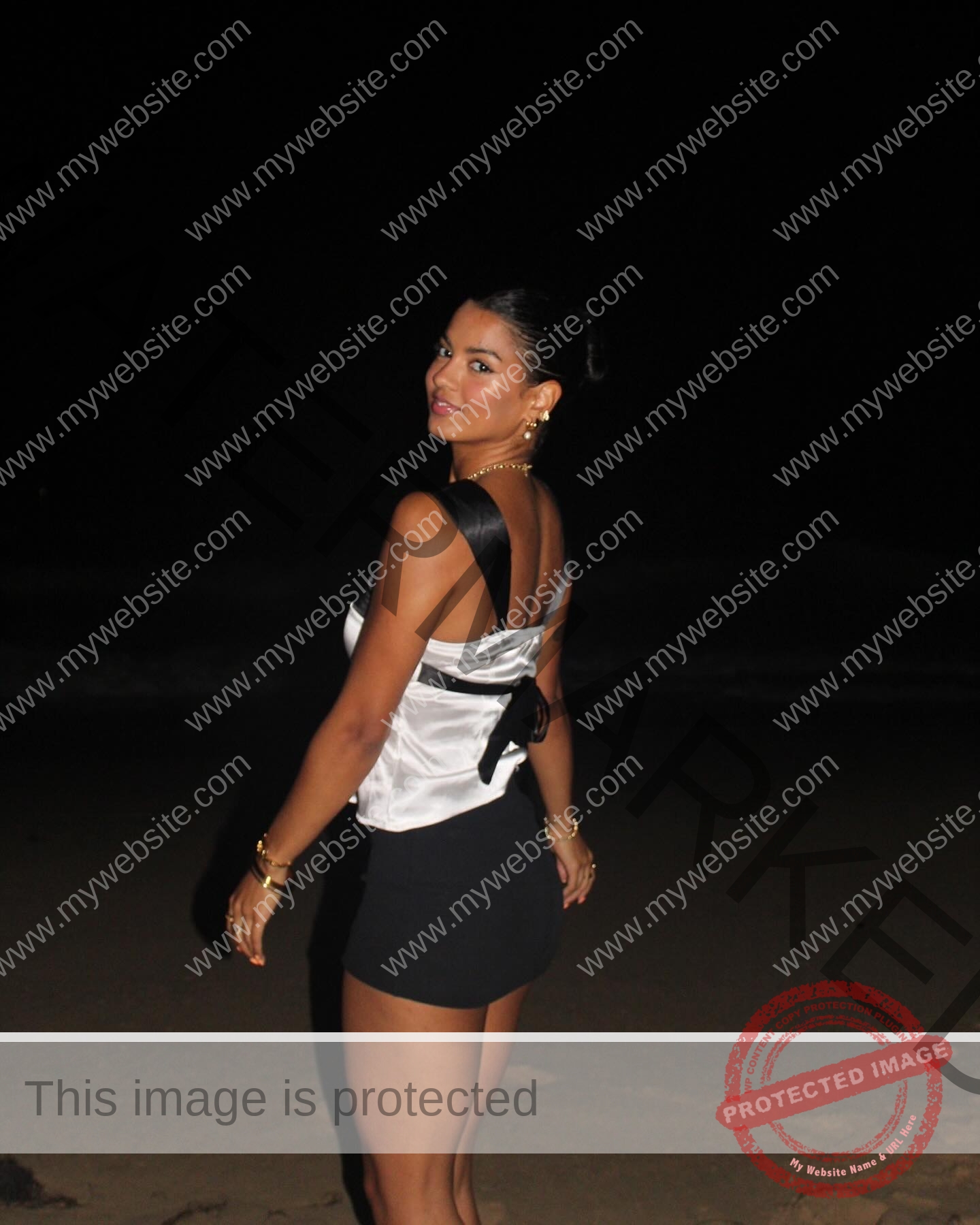 andrea-rivera-aviles-puerto-rico-aandrea.sofiaa-05911 Andrea Rivera Aviles, track athlete from Puerto Rico, stands on a dark beach at night, glancing back in a stylish outfit and gold jewelry.