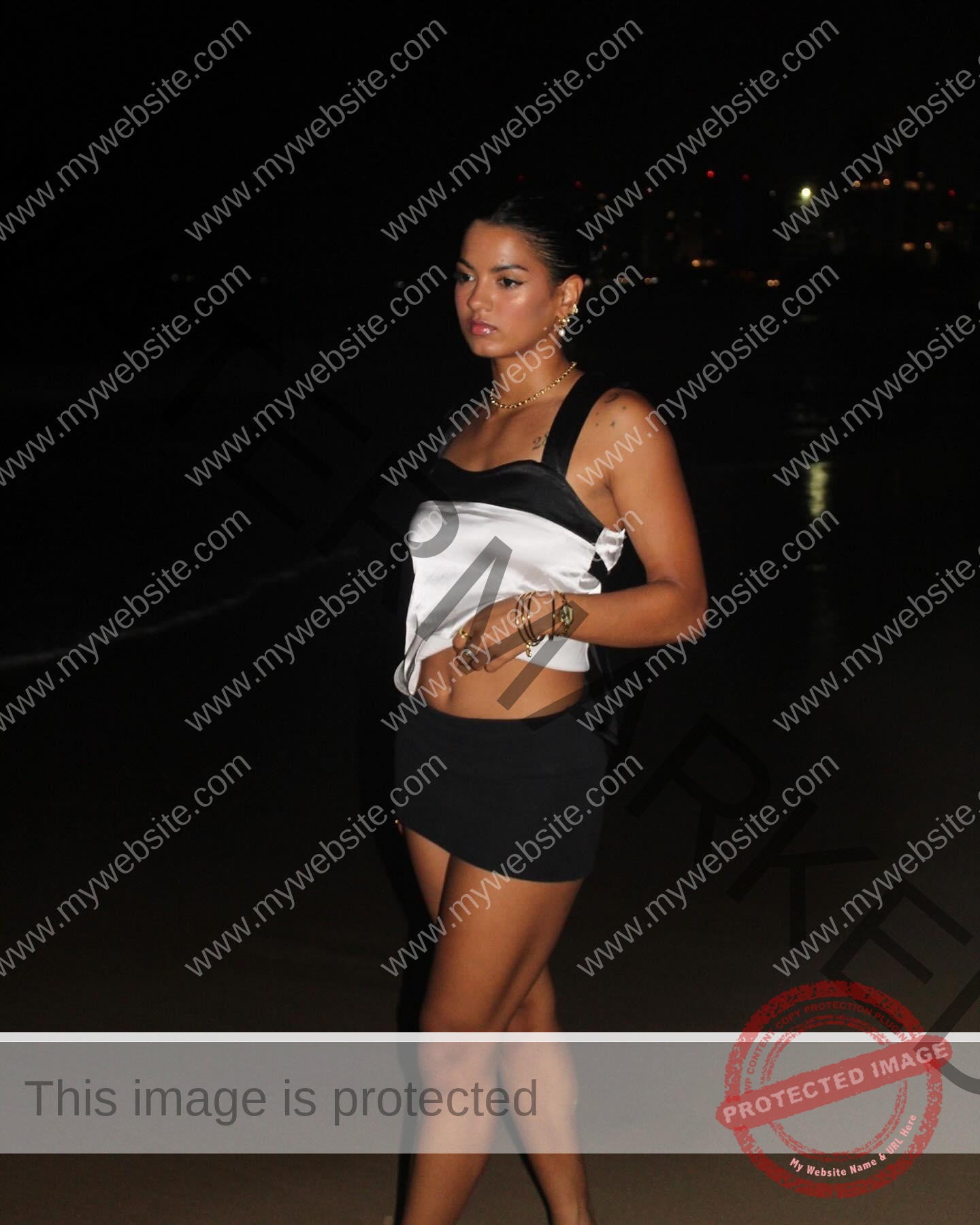 andrea-rivera-aviles-puerto-rico-aandrea.sofiaa-05913 Andrea Rivera Aviles, track athlete from Puerto Rico, walks on a beach at night in a black-and-white top, skirt, and gold jewelry.