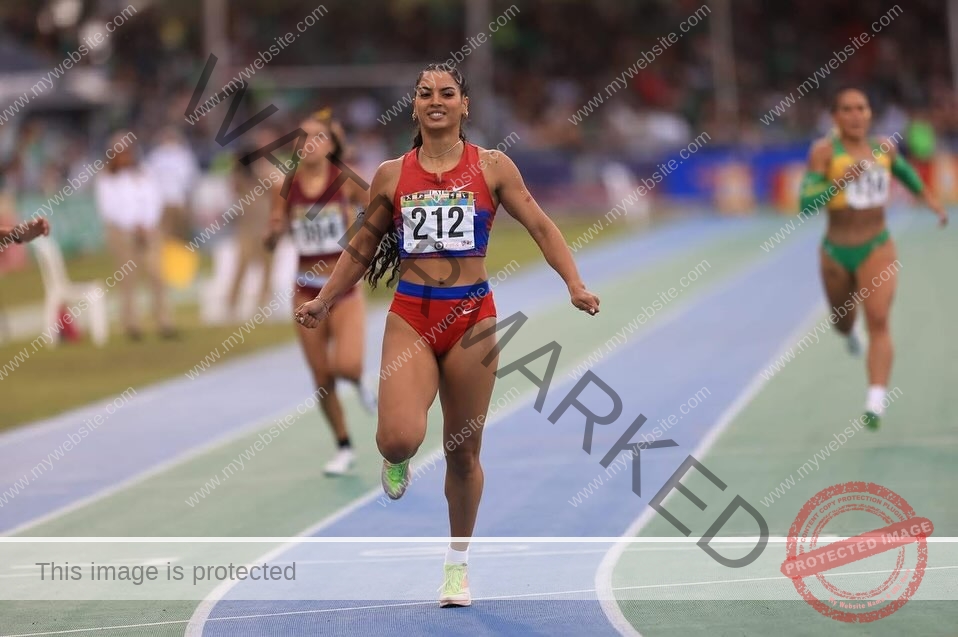 andrea-rivera-aviles-puerto-rico-aandrea.sofiaa-05932 Andrea Rivera Aviles, track athlete from Puerto Rico, in red with bib 212, finishes first on the track, smiling as runners follow.