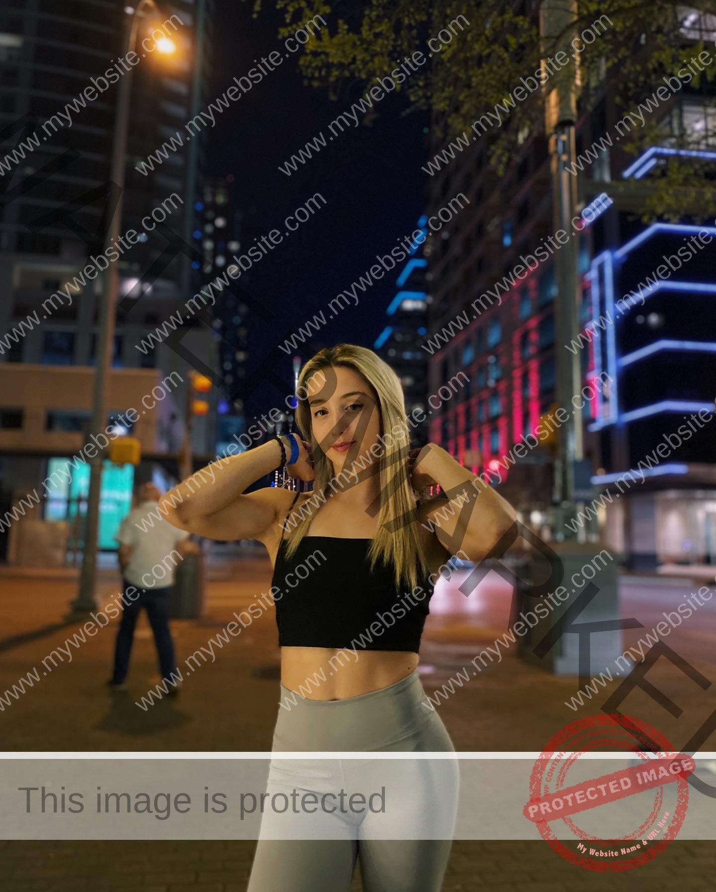 ariadni-adamopoulou-greece-ariadni_adam-08991 Ariadni Adamopoulou, pole vaulter from Greece and Oklahoma State, stands on a city street at night in a black crop top and gray leggings.