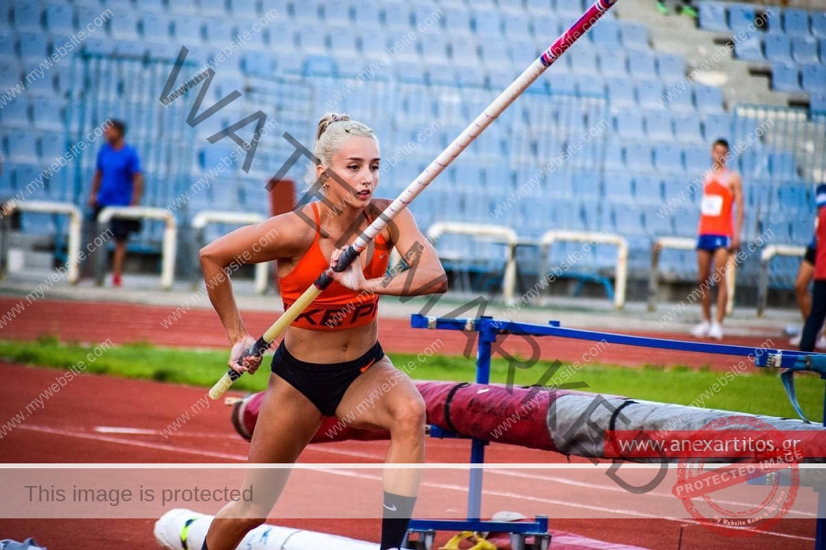 ariadni-adamopoulou-greece-ariadni_adam-08998 Ariadni Adamopoulou, pole vaulter from Greece and Oklahoma State, with blonde hair in orange top and black shorts runs with a pole.