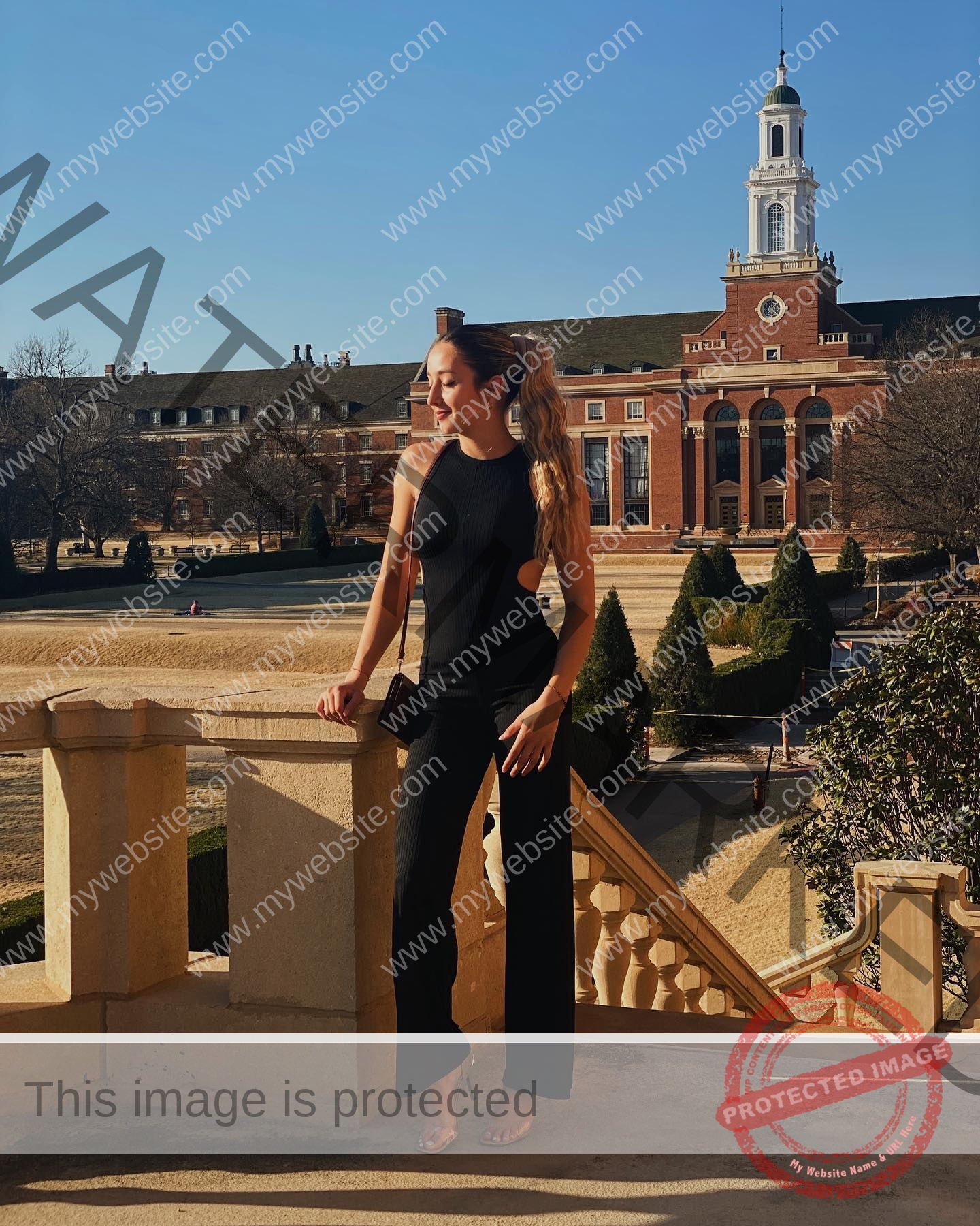 ariadni-adamopoulou-greece-ariadni_adam-09014 Ariadni Adamopoulou, pole vaulter from Greece and Oklahoma State, in a black jumpsuit on outdoor steps, smiling beside a brick building.