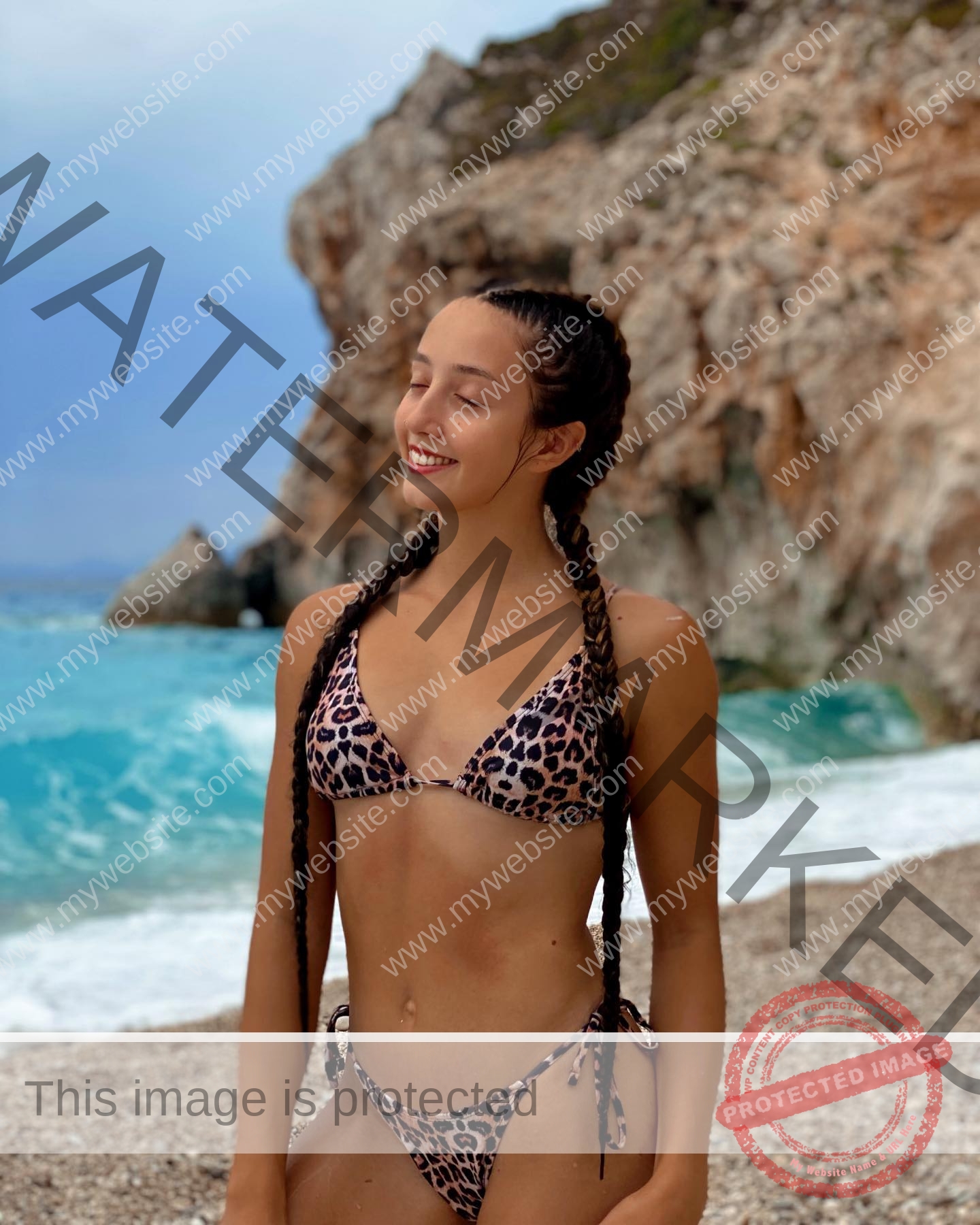 ariadni-adamopoulou-greece-ariadni_adam-09017 Ariadni Adamopoulou, pole vaulter from Greece and Oklahoma State, smiles with eyes closed on a rocky beach in a leopard bikini.