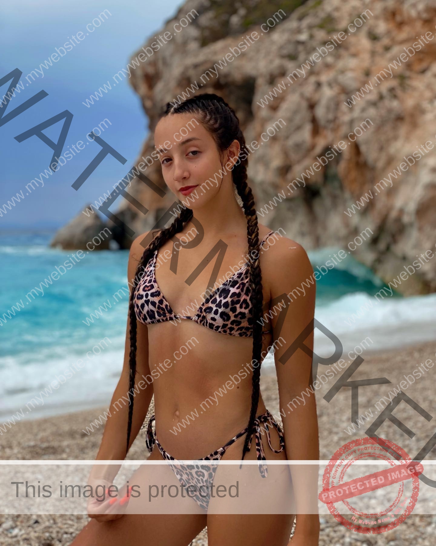 ariadni-adamopoulou-greece-ariadni_adam-09018 Ariadni Adamopoulou, pole vaulter from Greece and Oklahoma State, with long braided hair in a leopard bikini on a rocky beach.