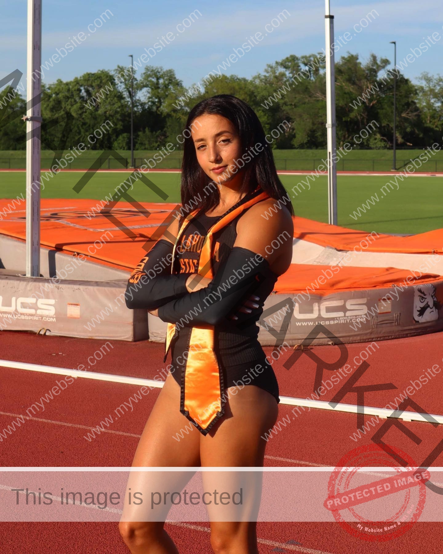 ariadni-adamopoulou-greece-ariadni_adam-09032 Ariadni Adamopoulou, pole vaulter from Greece and Oklahoma State, stands confidently on a track in her black and orange uniform.