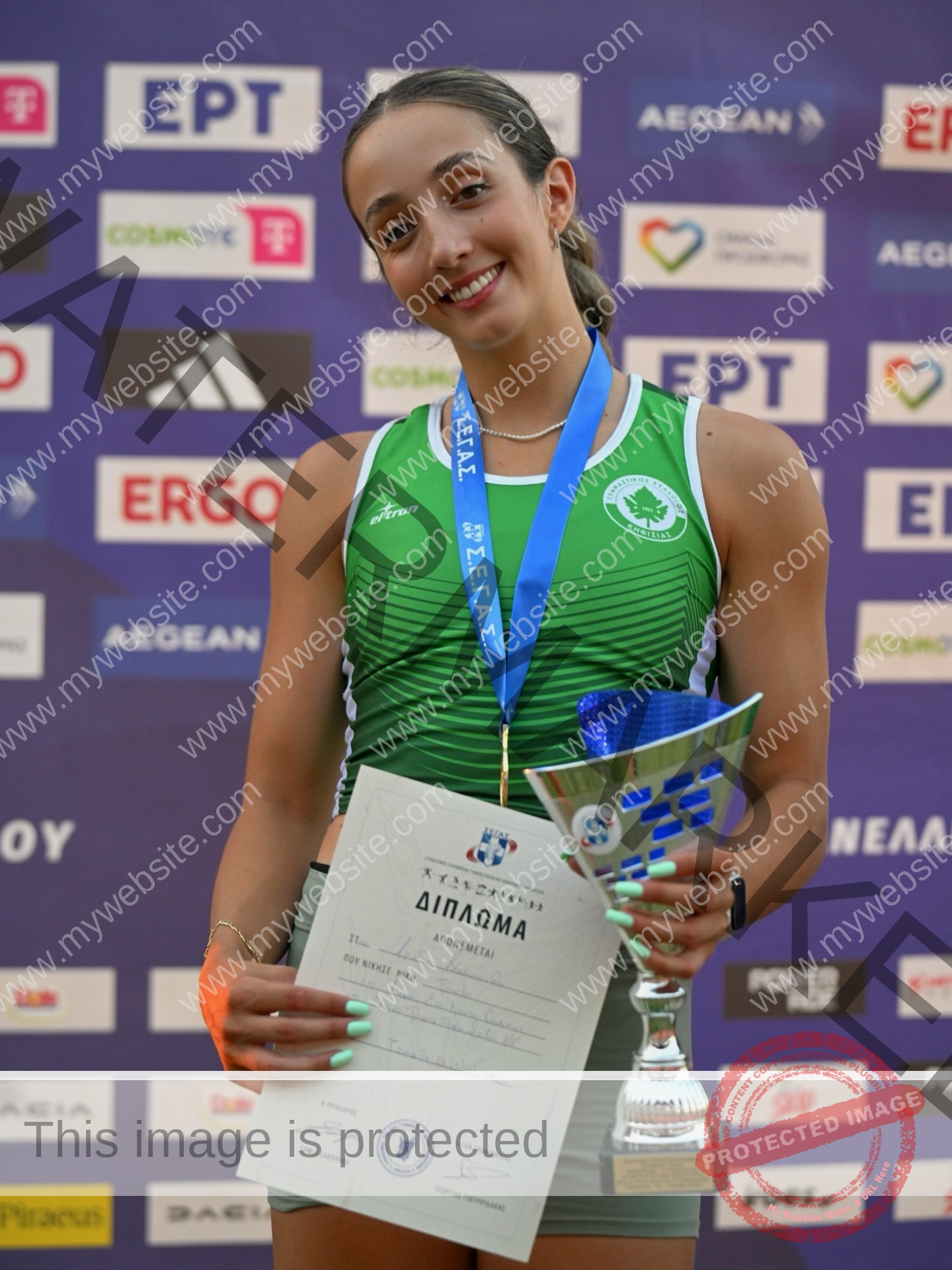 ariadni-adamopoulou-greece-ariadni_adam-09148 Ariadni Adamopoulou, pole vaulter from Greece and Oklahoma State, smiles in a green uniform holding trophy, certificate, and medal.