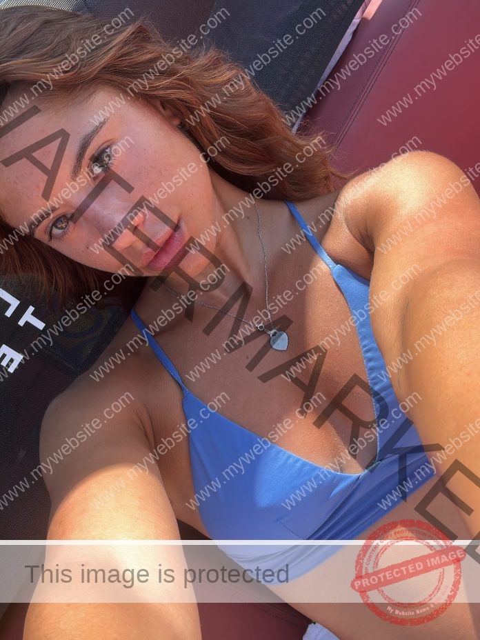 Beatrice Benaglia Beatrice Benaglia, a young woman with long brown hair, takes a selfie lying down in a blue bikini and heart necklace.
