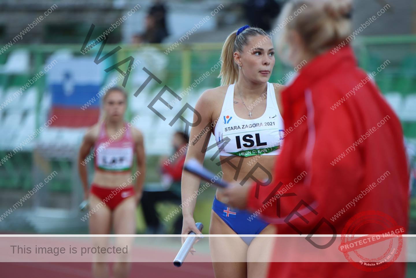 birna-kristjansdottir-iceland-birnakristink-10913 Birna-Kristjansdottir, track athlete from Iceland, in blue and white with baton on track; others in red, seats and flag behind.