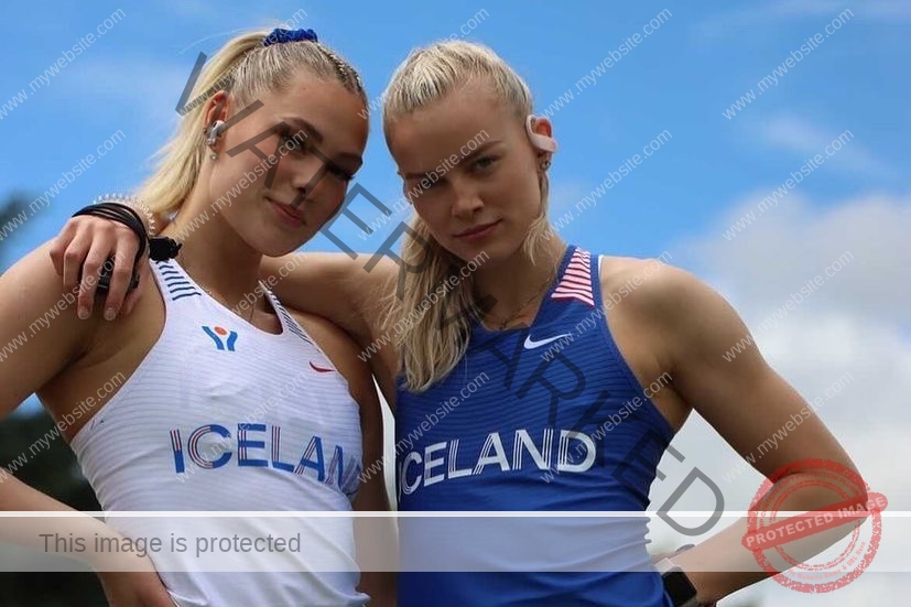 birna-kristjansdottir-iceland-birnakristink-10916 Birna-Kristjansdottir, track athlete from Iceland stands with another blonde athlete in blue and white uniforms under a bright sky.