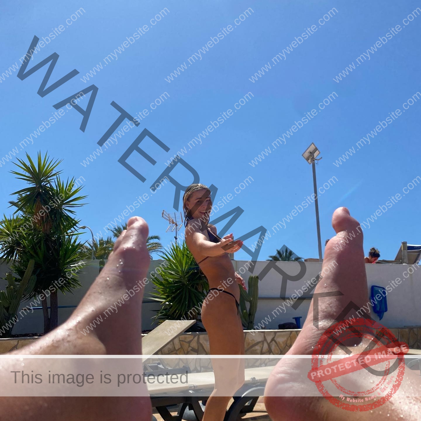 birna-kristjansdottir-iceland-birnakristink-10921 Birna-Kristjansdottir, track athlete from Iceland, in a black bikini stands by a pool, smiling; palm trees and feet frame the view.