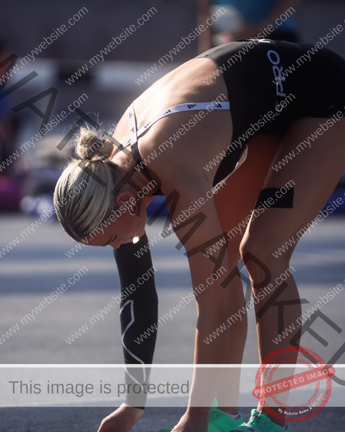 birna-kristjansdottir-iceland-birnakristink-10930 Birna-Kristjansdottir, track athlete from Iceland bends forward on the track in black gear and neon shoes, sunlight on her back.