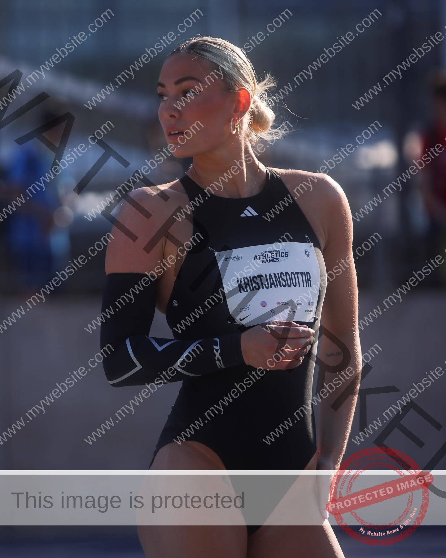 birna-kristjansdottir-iceland-birnakristink-10931 Birna-Kristjansdottir, track athlete from Iceland, stands outdoors in a black bodysuit and arm sleeve, looking to the side.
