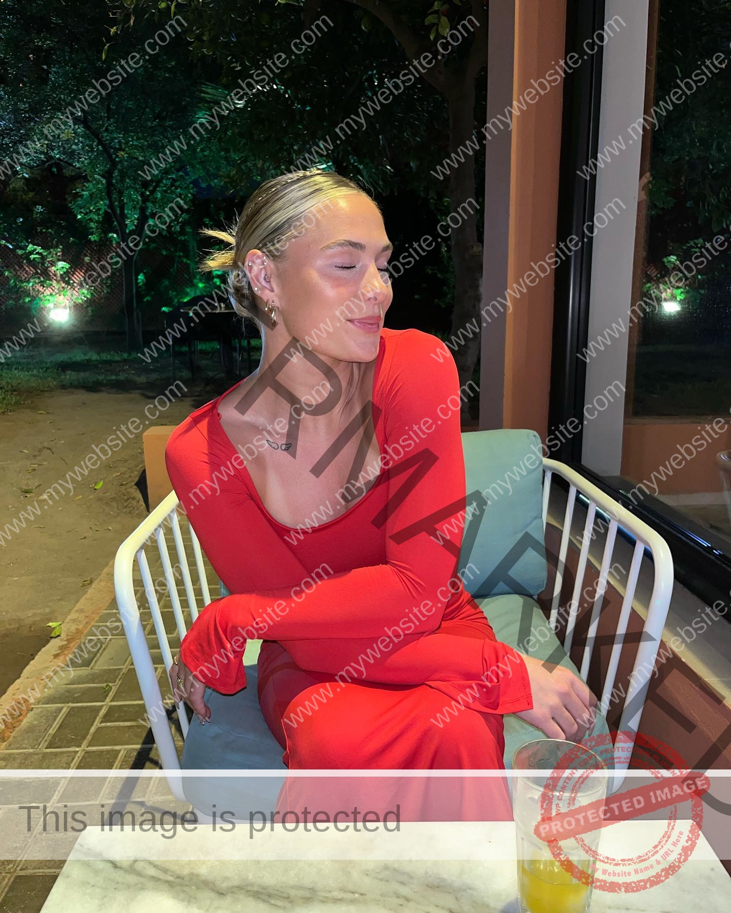 birna-kristjansdottir-iceland-birnakristink-10945 Birna-Kristjansdottir, track athlete from Iceland, in a red dress sits outside at night with an orange drink on the table nearby.