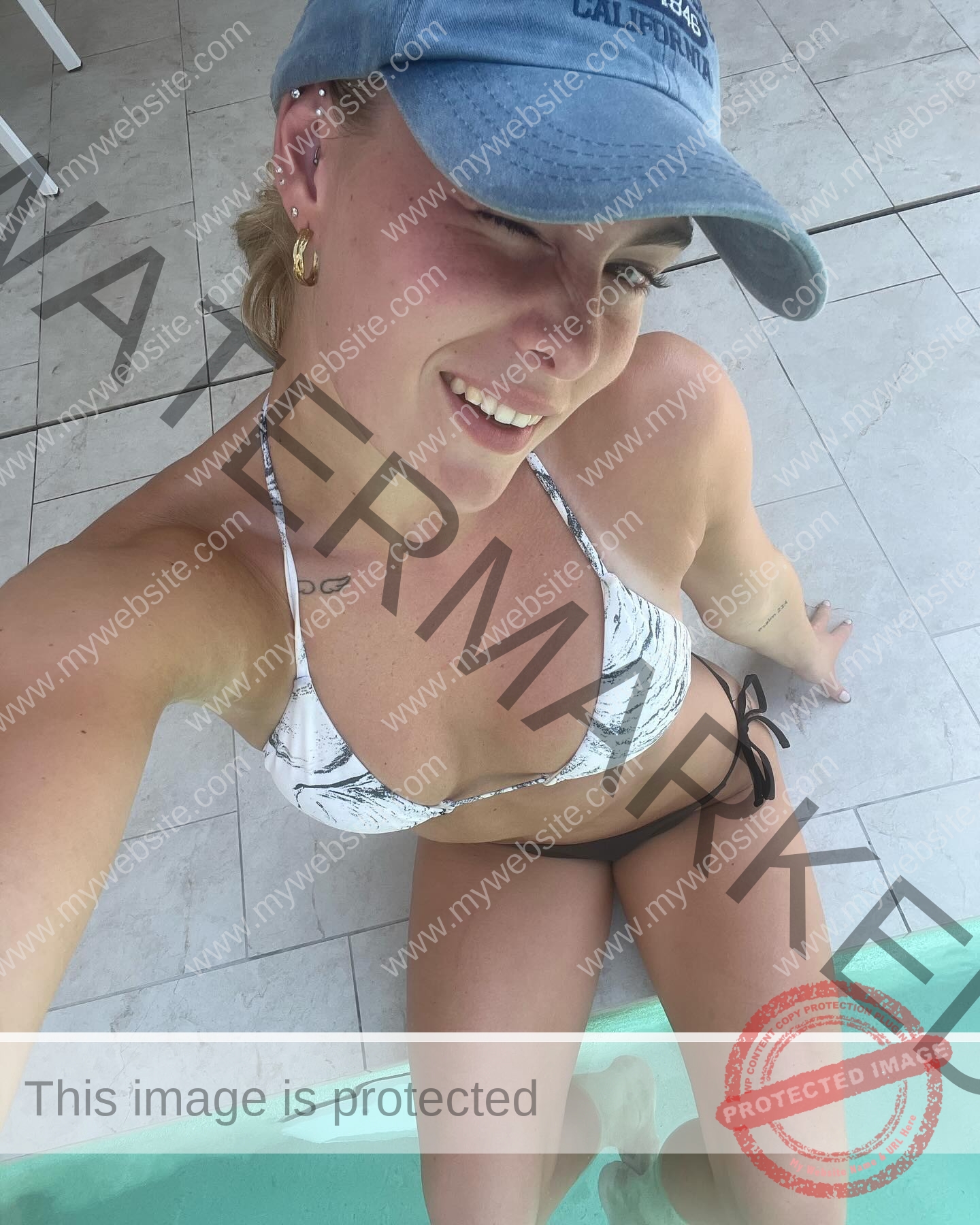 birna-kristjansdottir-iceland-birnakristink-10974 Birna-Kristjansdottir, track athlete from Iceland, wears a blue cap and bikini by the pool, smiling and winking as she dips her legs.