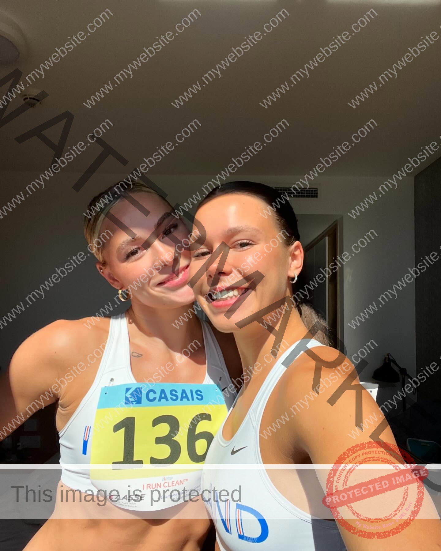 birna-kristjansdottir-iceland-birnakristink-10992 Birna-Kristjansdottir, track athlete from Iceland, and another female athlete smile for a selfie in sportswear; one has race bib 136.