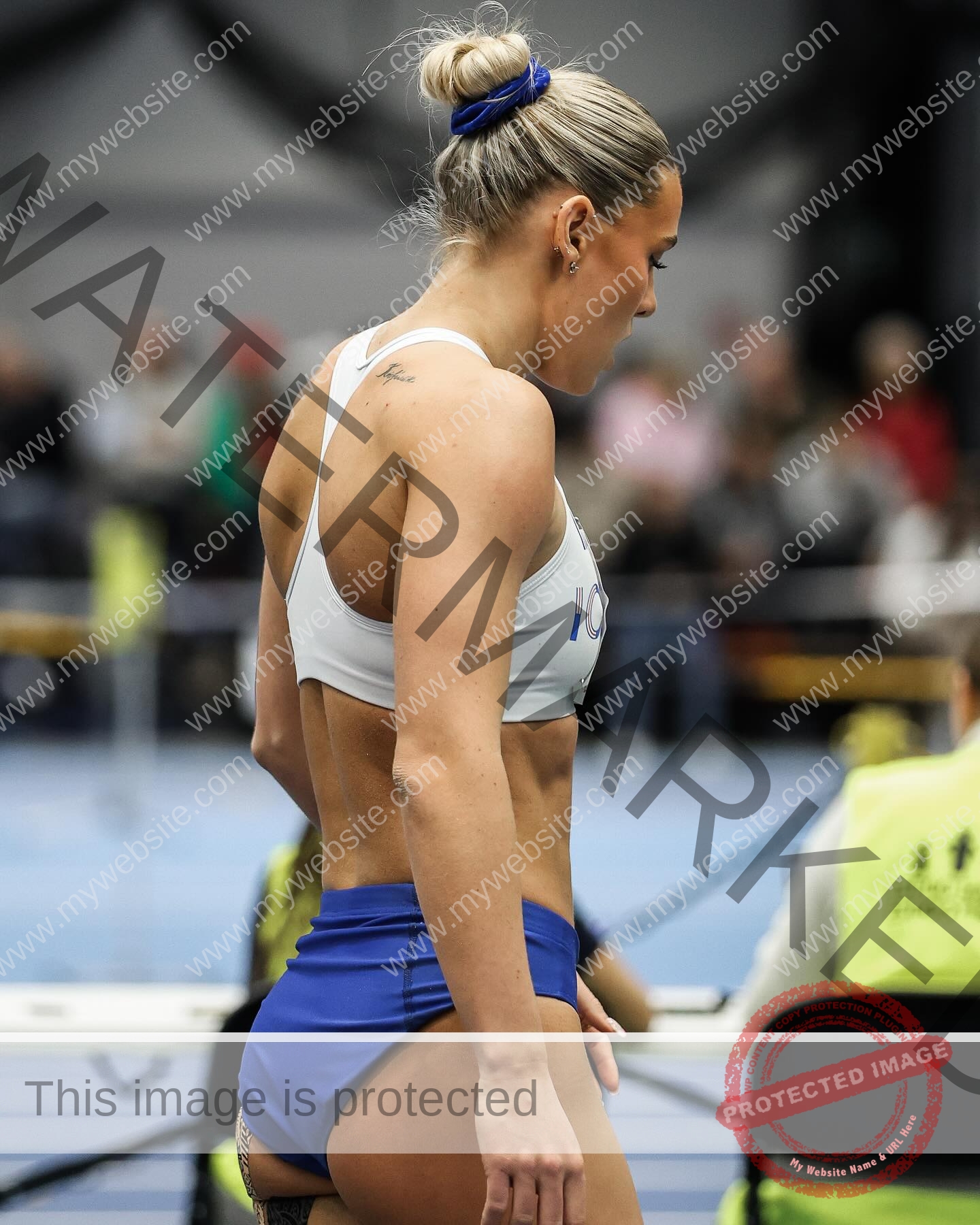 birna-kristjansdottir-iceland-birnakristink-11025 Birna-Kristjansdottir, track athlete from Iceland, with blonde hair in a bun, stands indoors at a track event in sportswear.