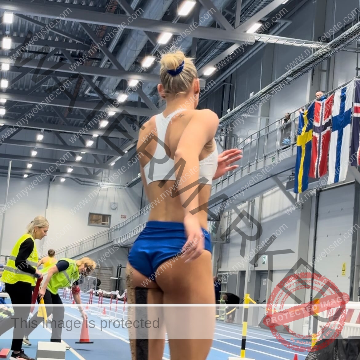 birna-kristjansdottir-iceland-birnakristink-11028 Birna-Kristjansdottir, track athlete from Iceland, in blue shorts and white sports bra prepares as officials and Swedish flag are seen.