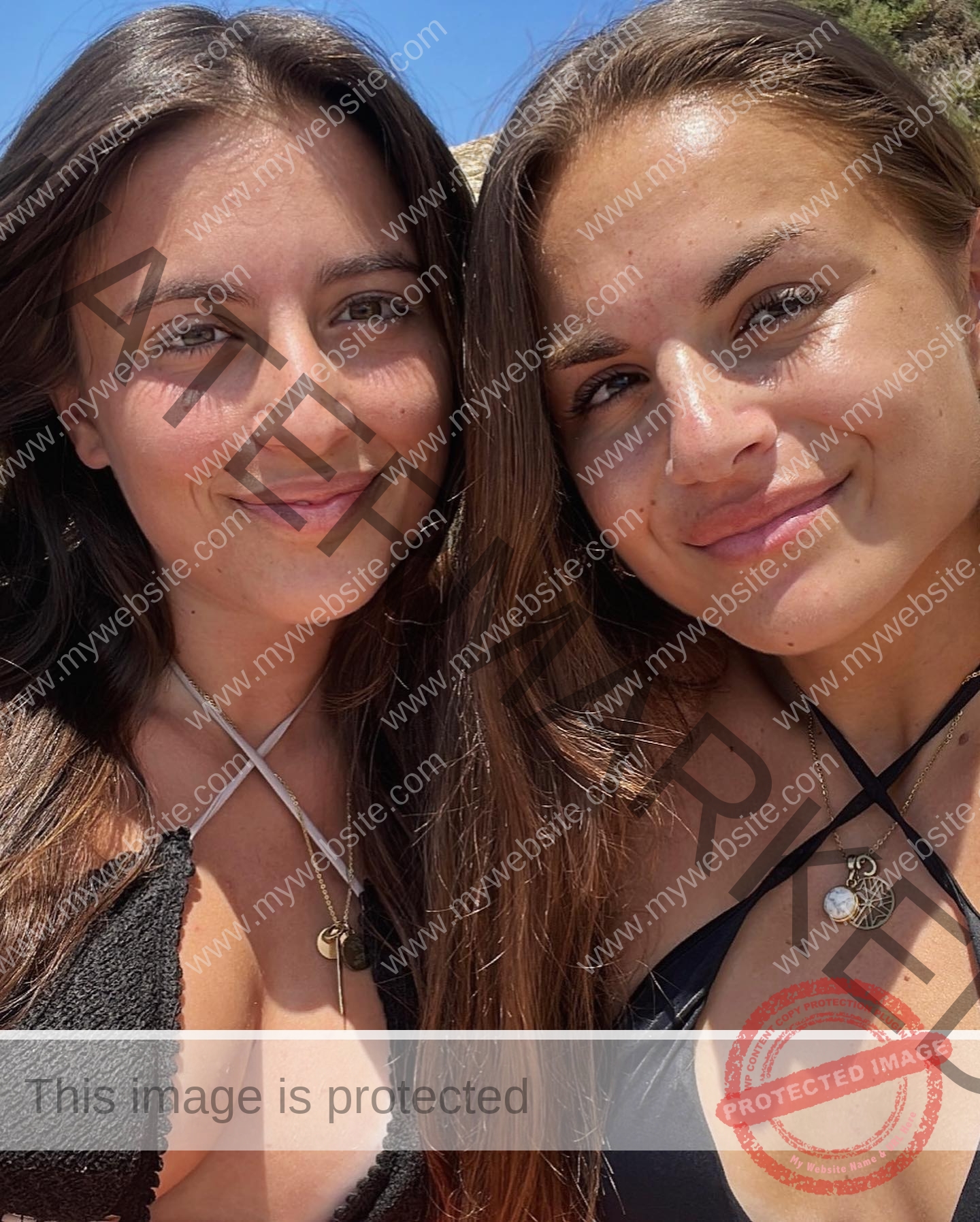 carla-scicluna-malta-carla.scicluna-01713 Carla Scicluna, track athlete from Malta, and another woman with long brown hair smile outdoors in black swimsuits under blue sky.