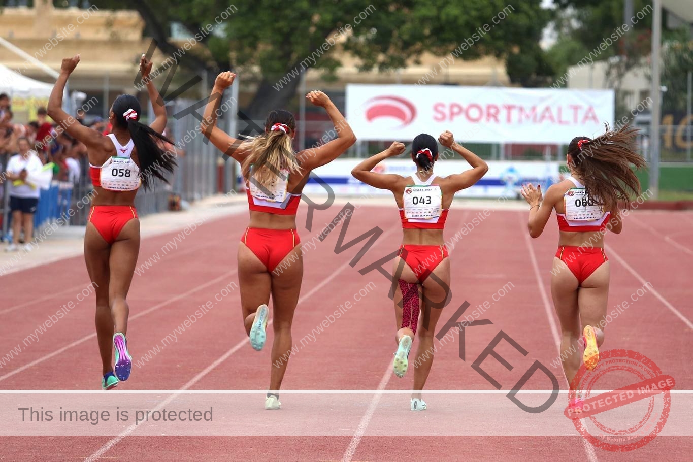 carla-scicluna-malta-carla.scicluna-01742 Carla Scicluna, track athlete from Malta, celebrates with teammates in red uniforms crossing the finish line; SportMalta banner behind.