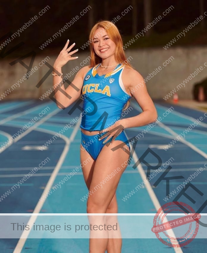 Catherine Leger, track star from UCLA and Canada, stands on a blue track in her uniform, smiling and holding up four fingers.