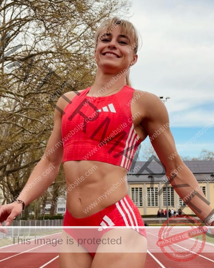 Catia Gubelmann A smiling athlete, Catia Gubelmann, in a red sports crop top and shorts with white stripes, stands on a Swiss outdoor track.