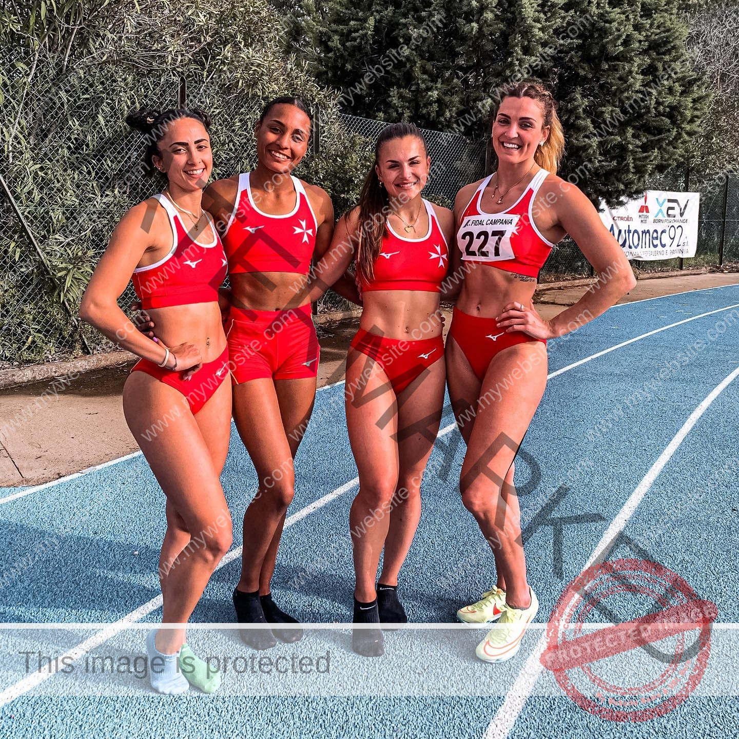 charlotte-wingfield-malta-charlottewingfield.oly-03721 Charlotte Wingfield, track athlete from Malta, stands with three teammates in red sportswear on a blue track; bib 227 is visible.