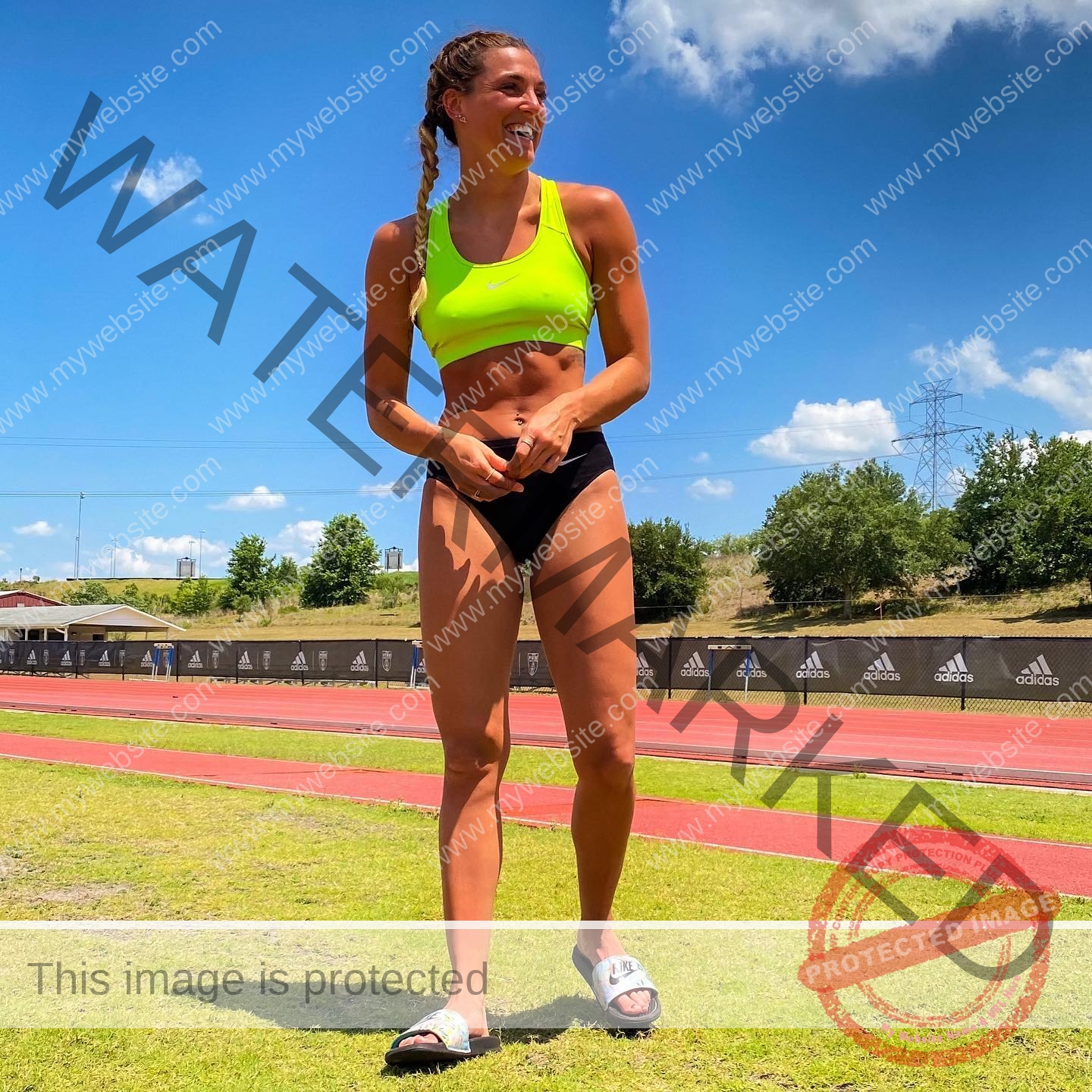 charlotte-wingfield-malta-charlottewingfield.oly-03725 Charlotte Wingfield, track athlete from Malta, in neon yellow sports bra and black shorts smiles on a sunny track with trees behind.