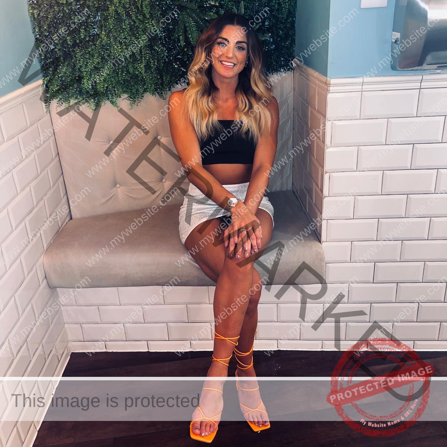 charlotte-wingfield-malta-charlottewingfield.oly-03788 Charlotte Wingfield, track athlete from Malta, sits on a cushioned bench in a black crop top, light skirt, orange heels, smiling.